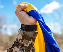 Photo d’un militaire tenant le drapeau de l’Ukraine dans son poing.