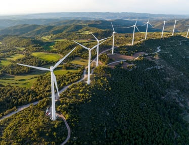 An aerial view of wind turbines in the mountains, harnessing renewable energy from the natural wind resources.