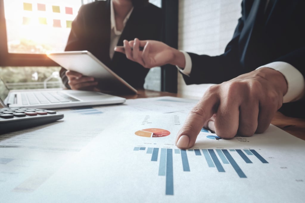 Hands pointing to a bar chart in a financial report.