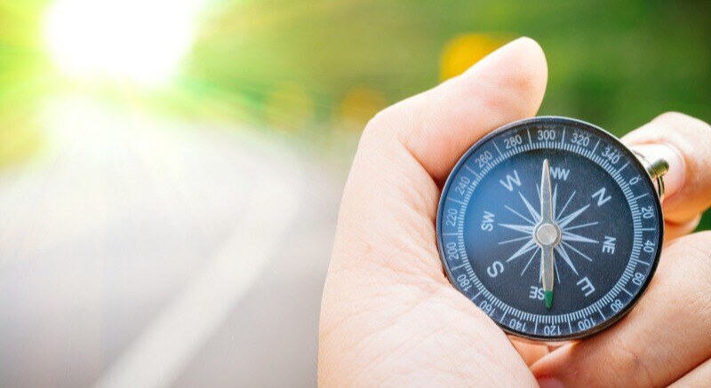 A close-up image of a hand holding a compass