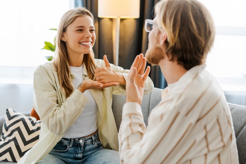 Happy, smiling couple, young man and woman communicating using sign language at home
