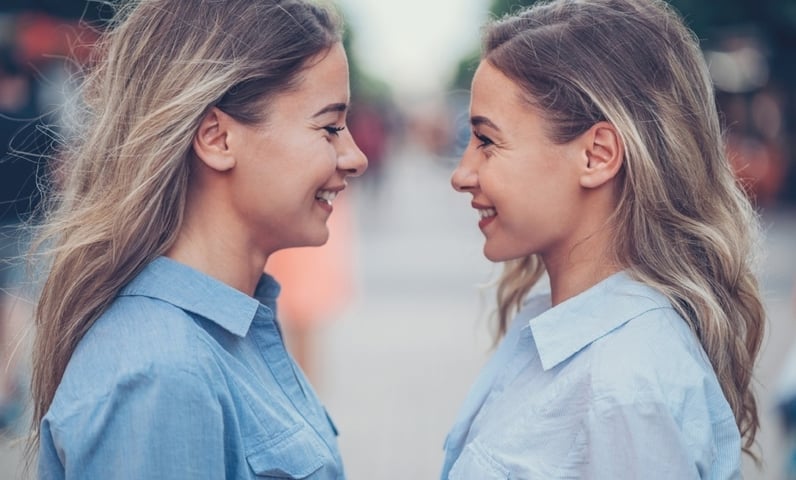 Le profil de deux femmes qui ont une forte ressemblance, l’une d’âge mûr, l’autre plus jeune, se faisant face. Toutes deux sourient, ont des cheveux longs et blonds et portent une chemise bleue.