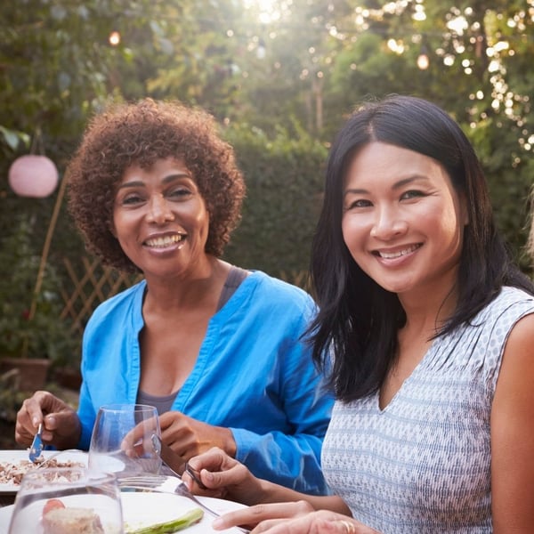 A portrait of two mature women smiling and enjoying a meal outdoors