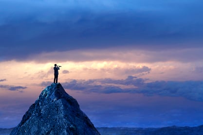 A man looking through a telescope on top of a mountain.