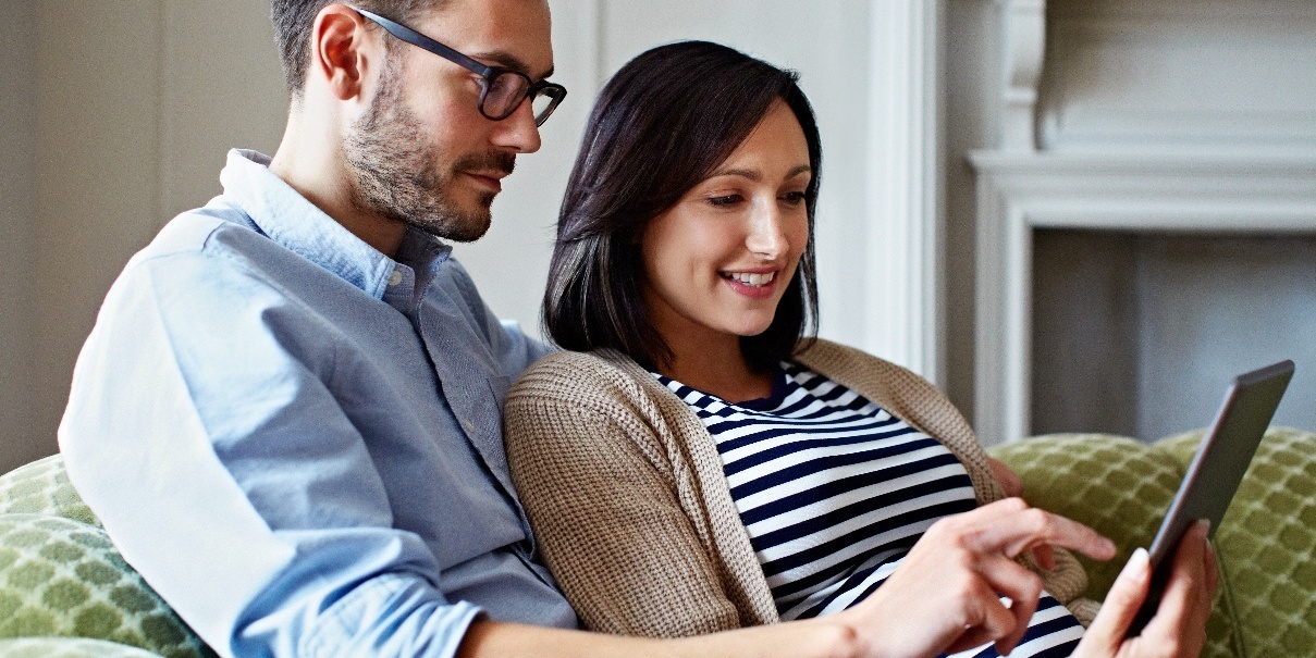 Young man and expecting woman looking at tablet